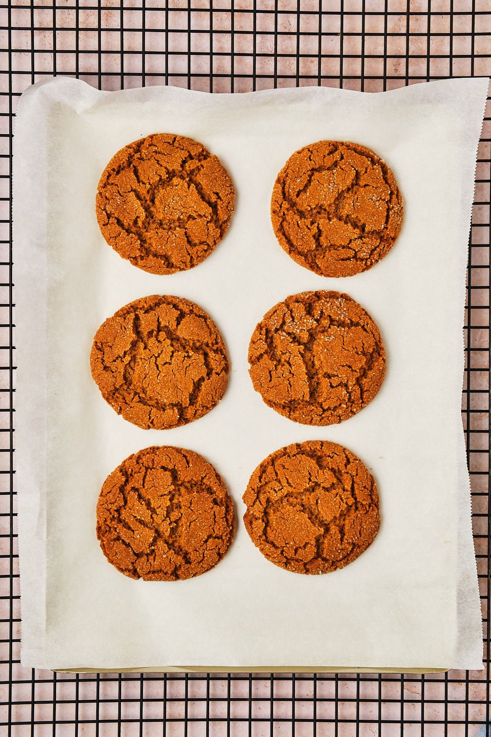 Vegan ginger cookies on a baking tray on a wire rack, cooling.