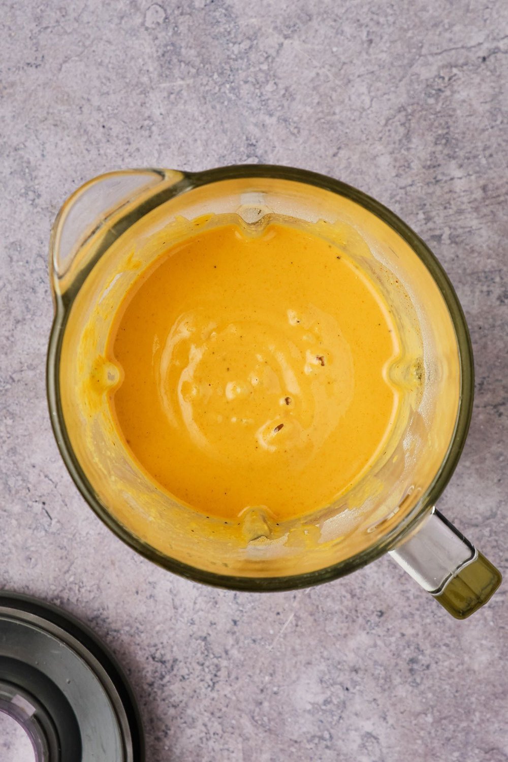 A top-down view of blended cheddar-Gruyère cheese mixture in a blender jar.