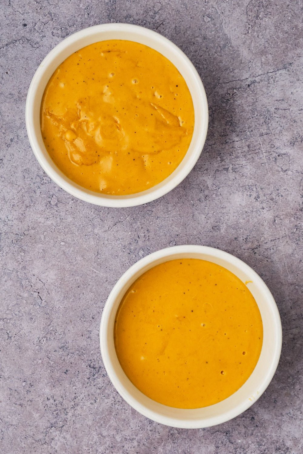 Vegan cheddar-Gruyère cheese mixture cooling in two bowls.