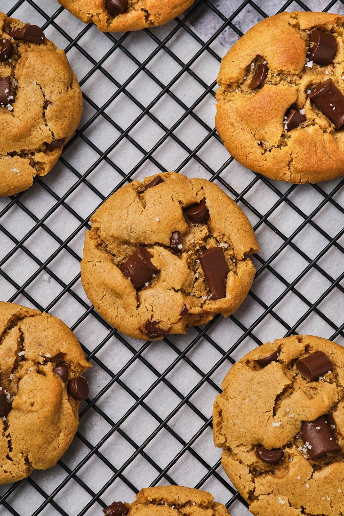 A top-down view of vegan chocolate chip cookies cooling on a wire rack.