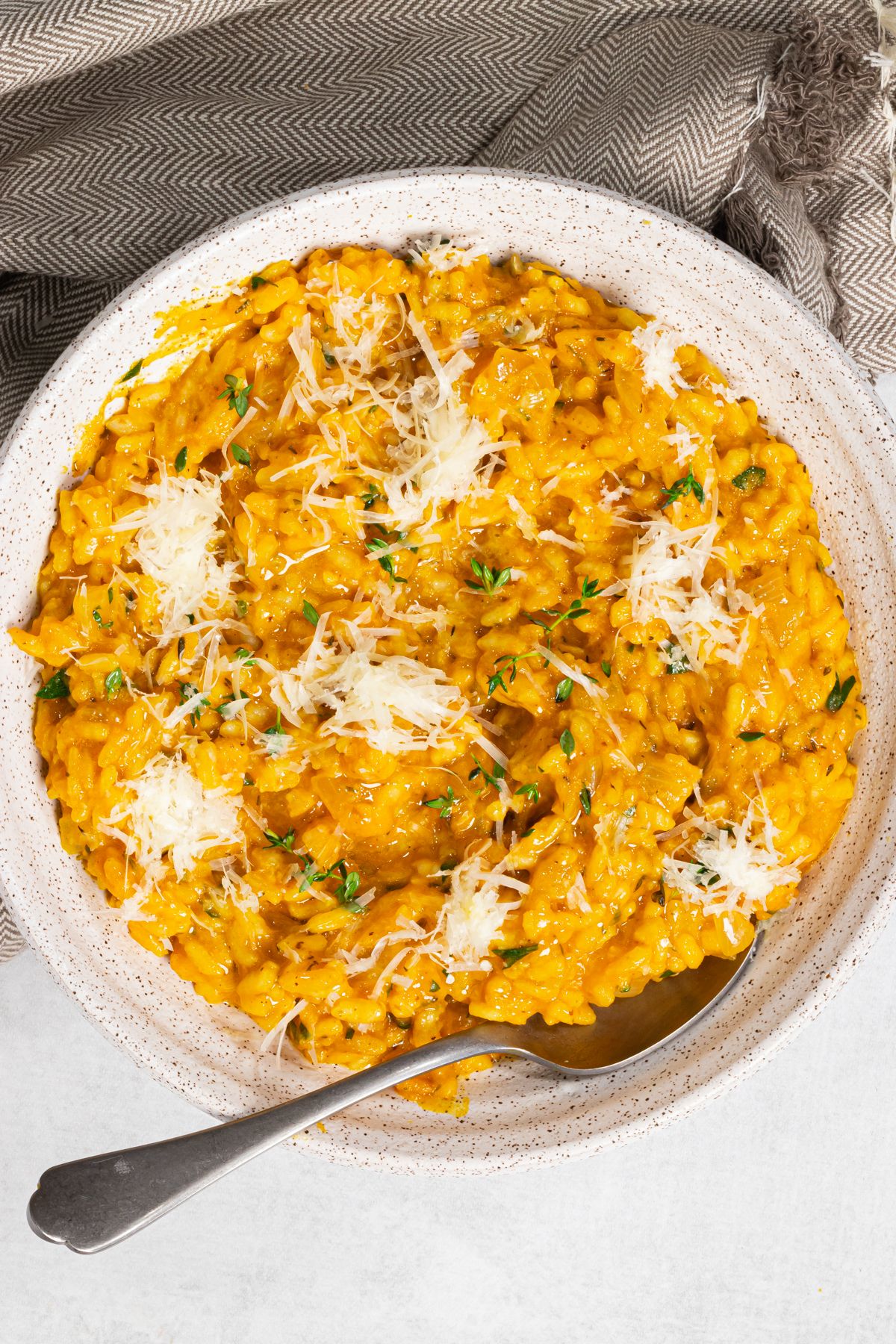 Pumpkin Risotto in a Bowl with a spoon, topped with vegan parmesan.