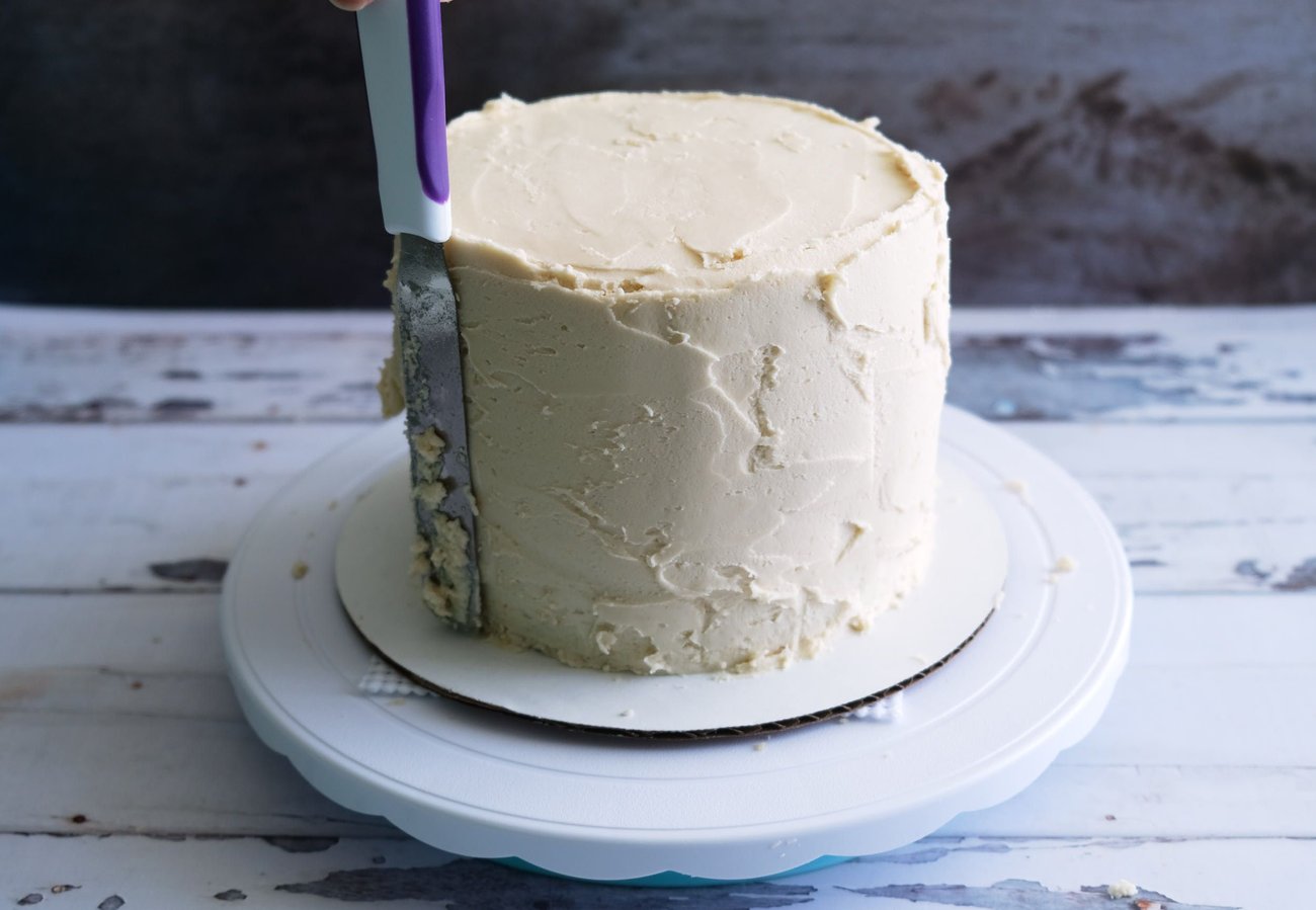 Spread a thicker layer over your base frosting layer using a spatula. Then use the icing smoother to smooth it out.