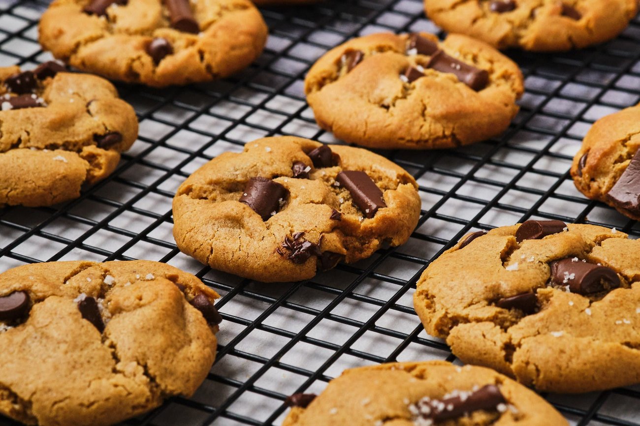 A side angle view of vegan chocolate chip cookies cooling on a wire rack.