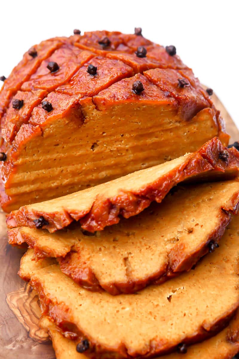 Vegan seitan ham on a platter, sliced. 