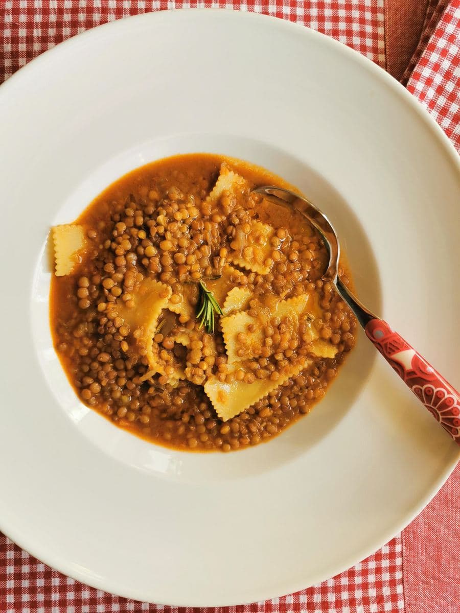 A top-down view of Umbrian lentil soup with pasta in a bowl with a spoon. 