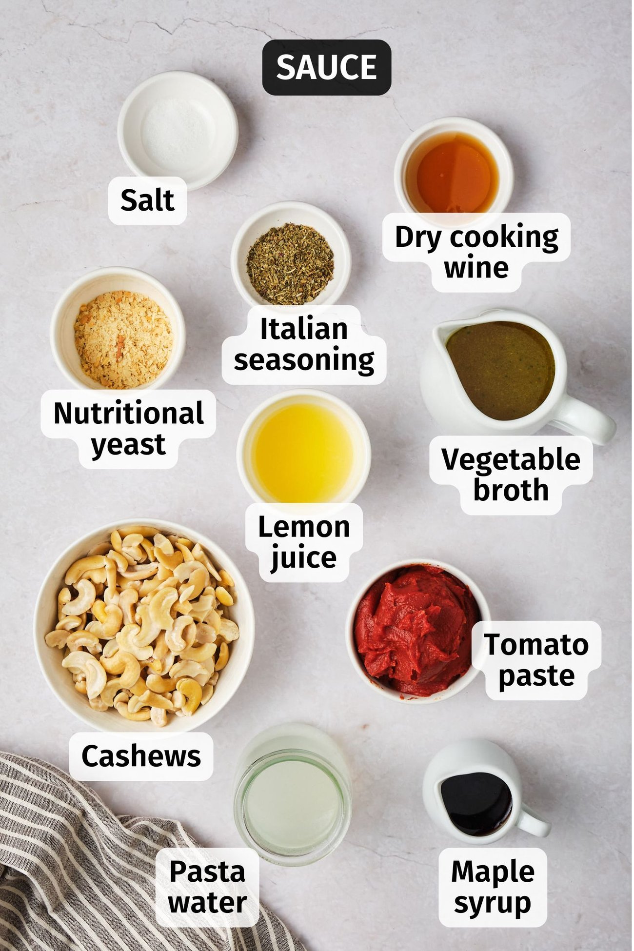 The ingredients for vegan creamy tomato pasta sauce in bowls on a table, labeled. 