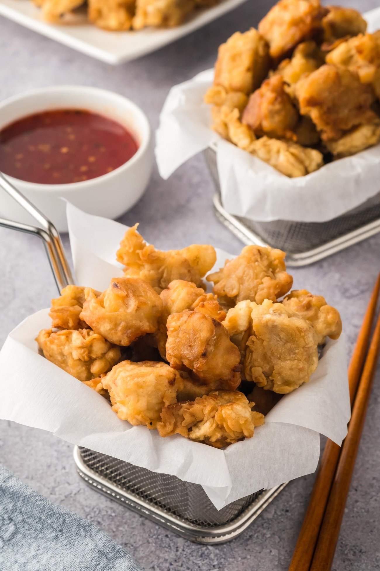 Deep-fried tofu served in fryer baskets, with a side of sauce. 