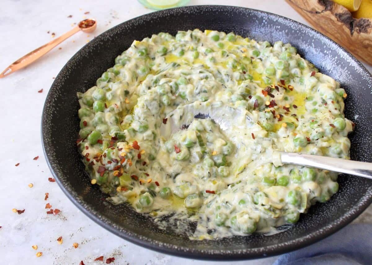 Creamed peas and leeks in a bowl with a spoon.