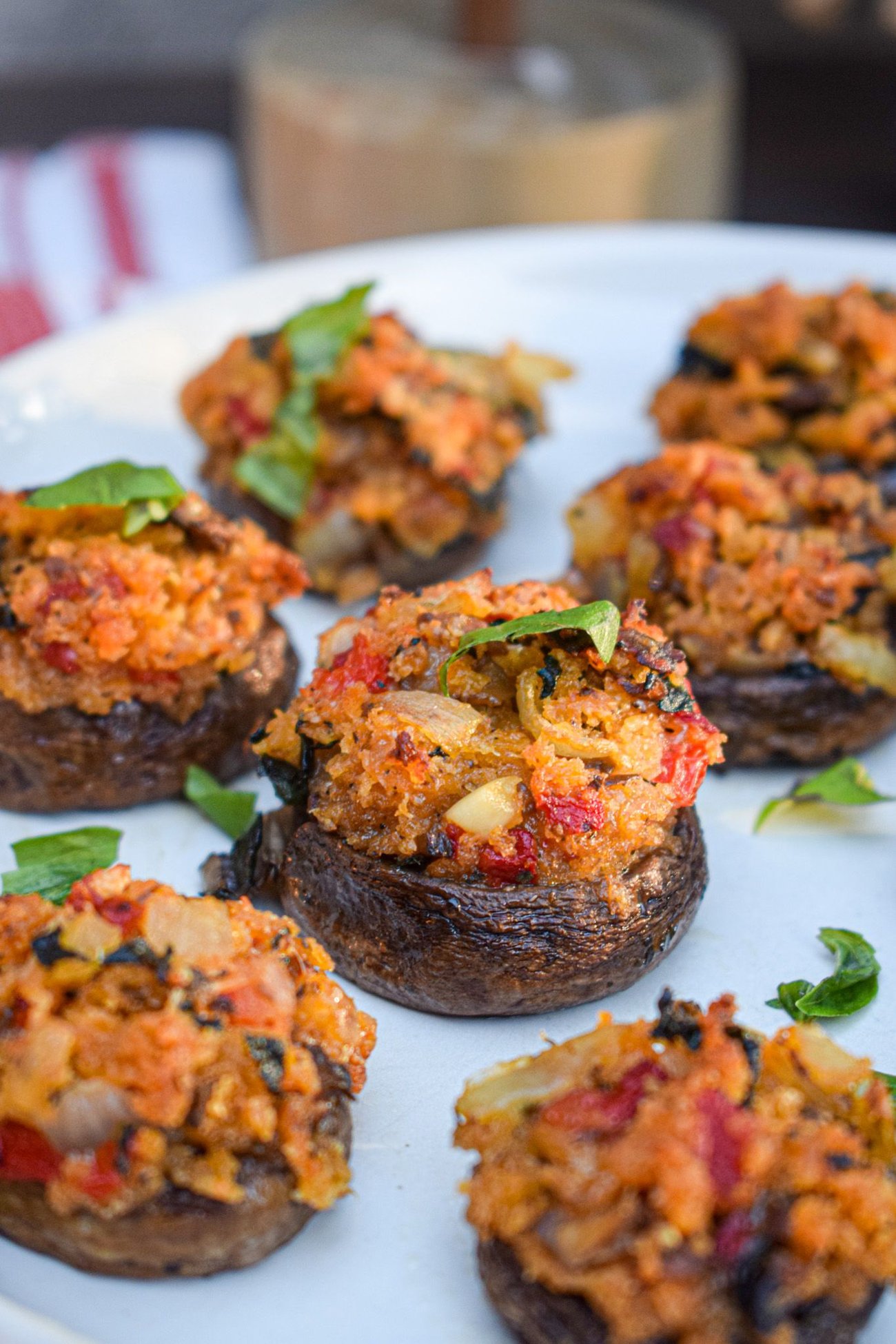Vegan Italian stuffed mushrooms on a plate topped with herbs.
