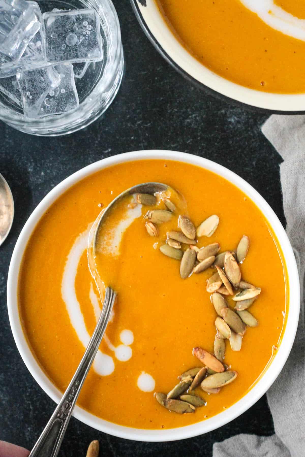 Vegan butternut squash apple soup in a bowl with a spoon.