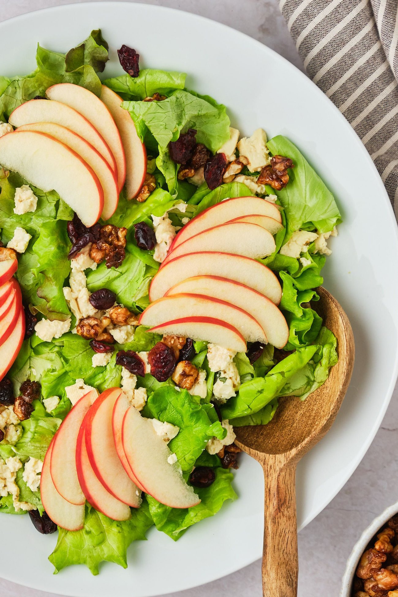 Close-up view of apple walnut salad in a bowl with a serving spoon.