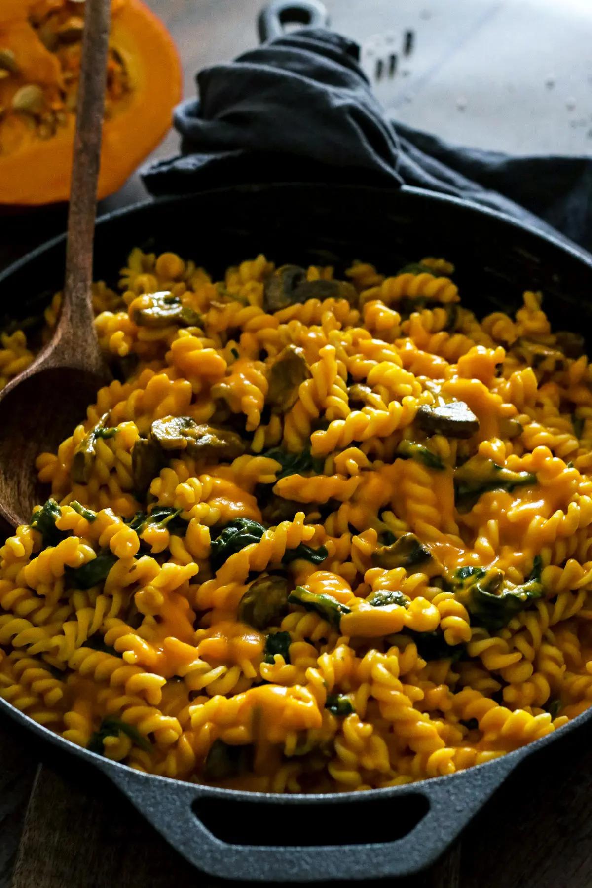 Pumpkin pasta in a skillet with a serving spoon.