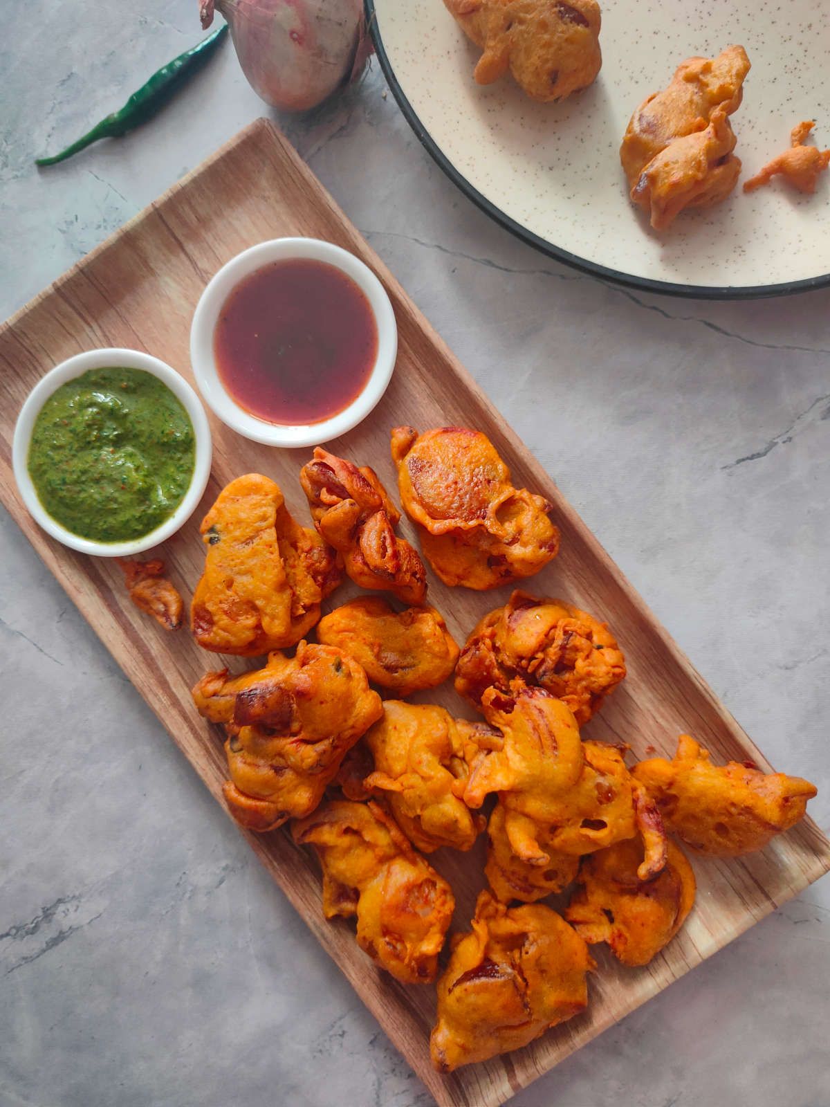 Vegan onion pakora on a platter with dipping sauces.