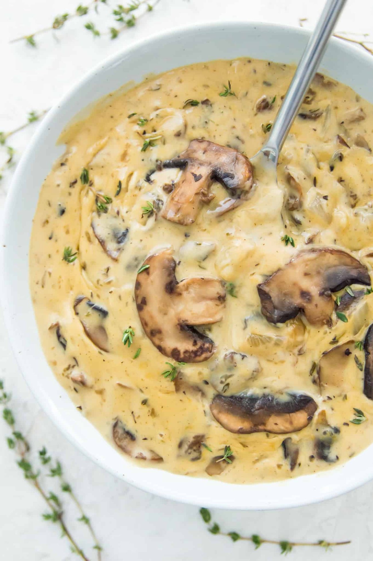 A close-up view of vegan cream of mushroom soup in a bowl with a spoon. 