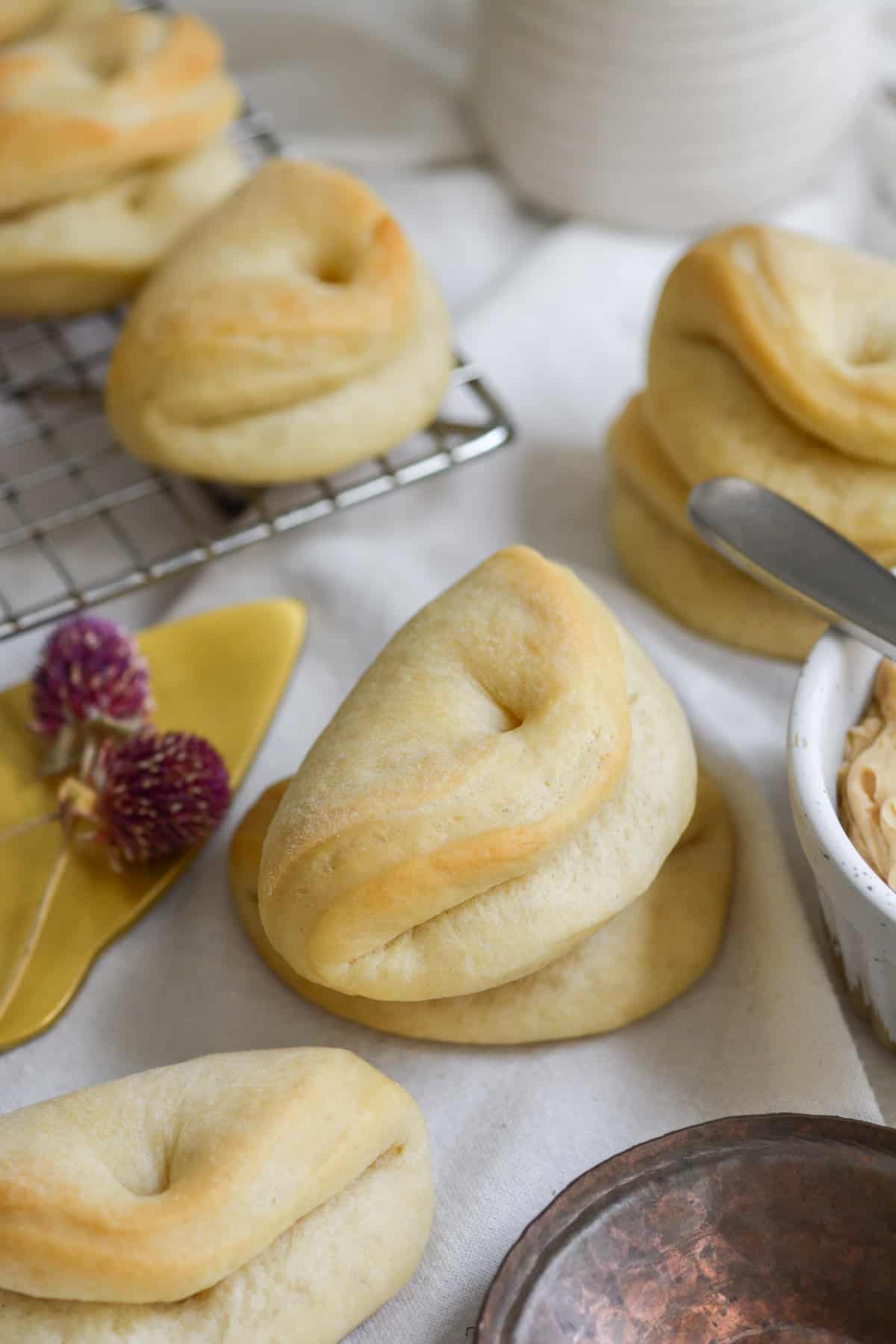 Vegan Parker House Dinner Rolls on a cooling rack and tablecloth.