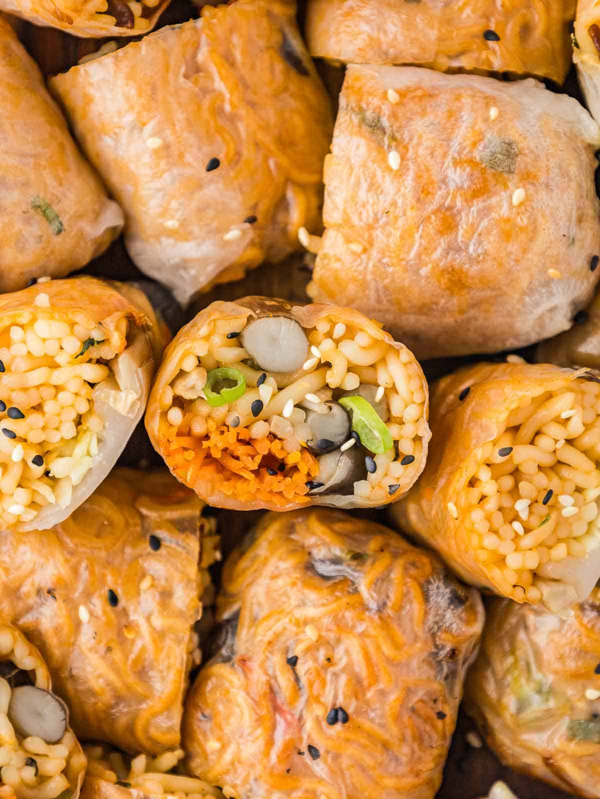 Spicy ramen noodle spring rolls, with a few cut and turned upward to show their contents. 