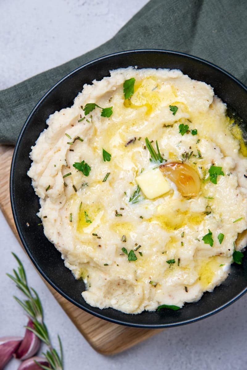 Roasted Mashed Cauliflower in a bowl with garlic and herbs.