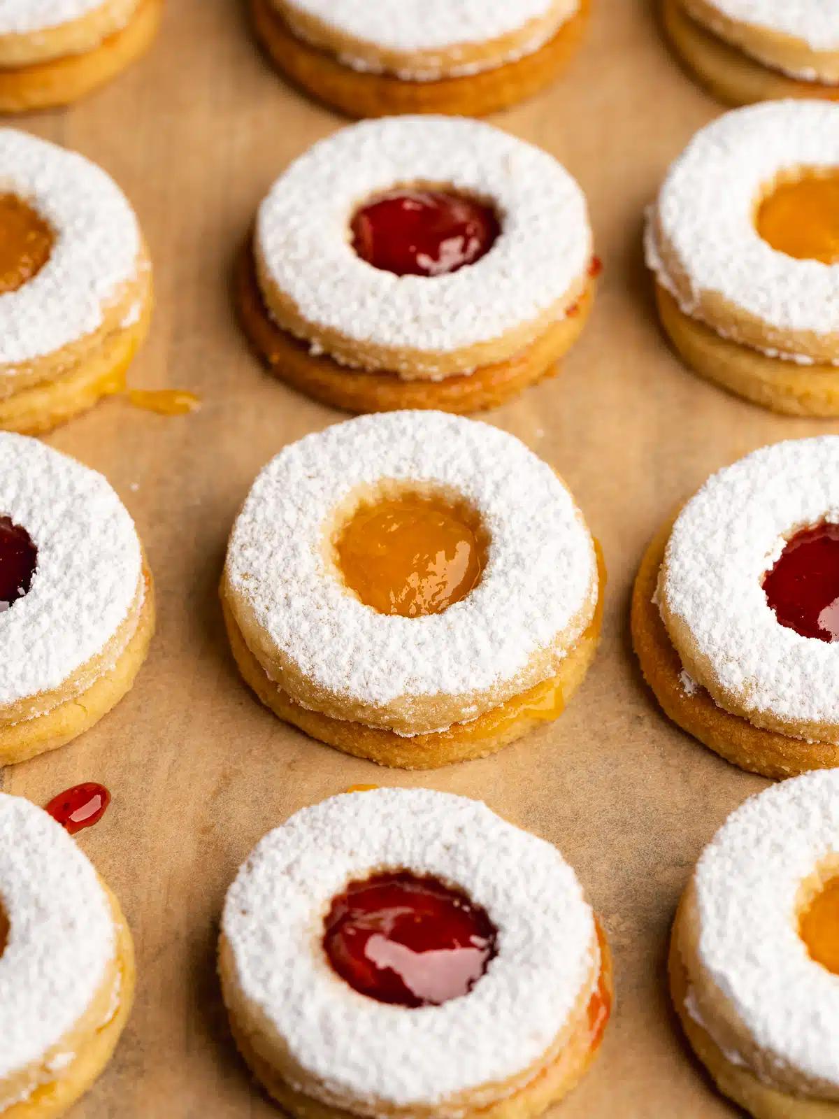 Vegan Linzer cookies on parchment paper, dusted with powdered sugar. 