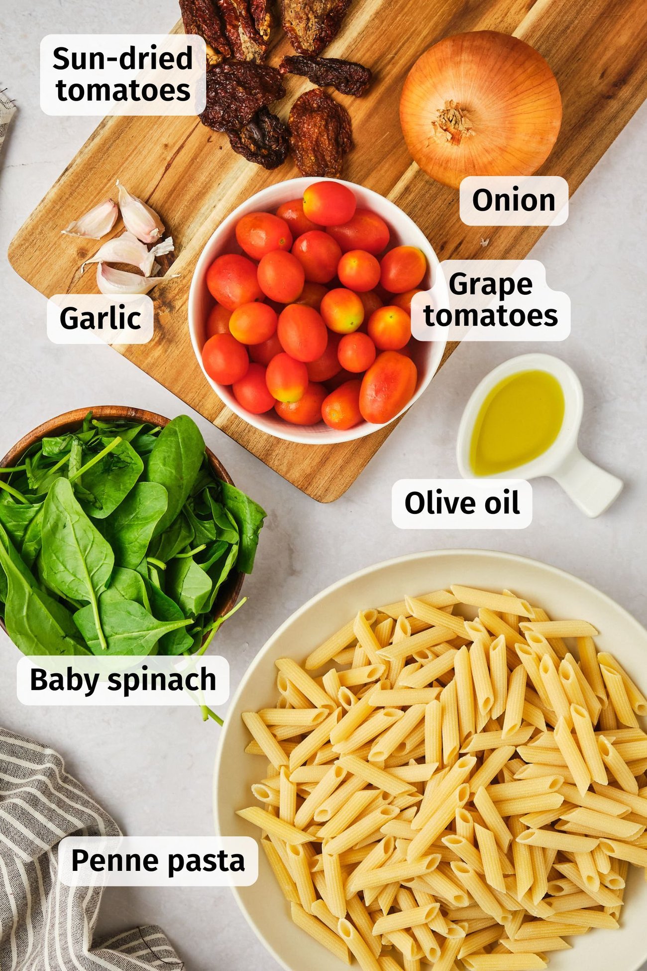 The ingredients for vegan creamy tomato pasta (except the sauce) on a table, labeled.