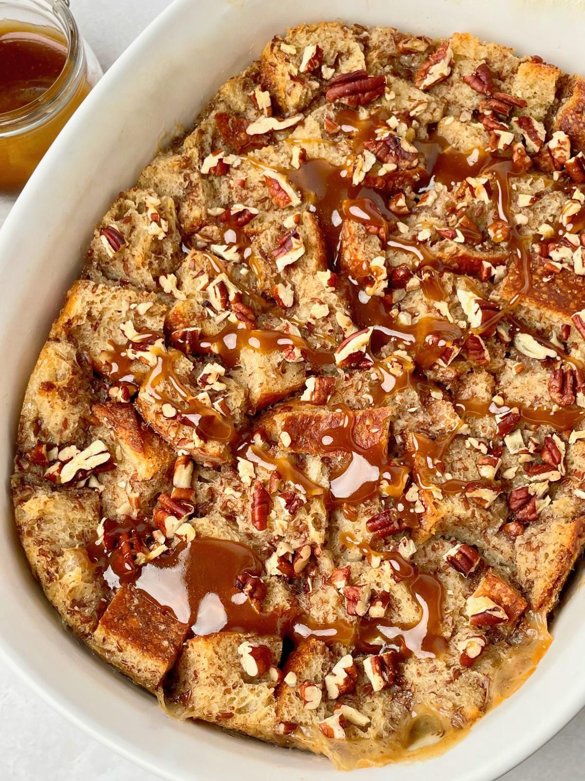 Vegan bread pudding in a casserole dish with a dairy-free butterscotch sauce.