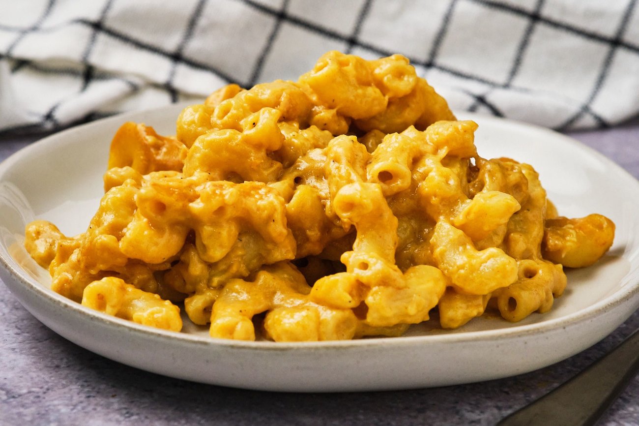 Vegan mac and cheese, served on a small plate, with a linen in the background.