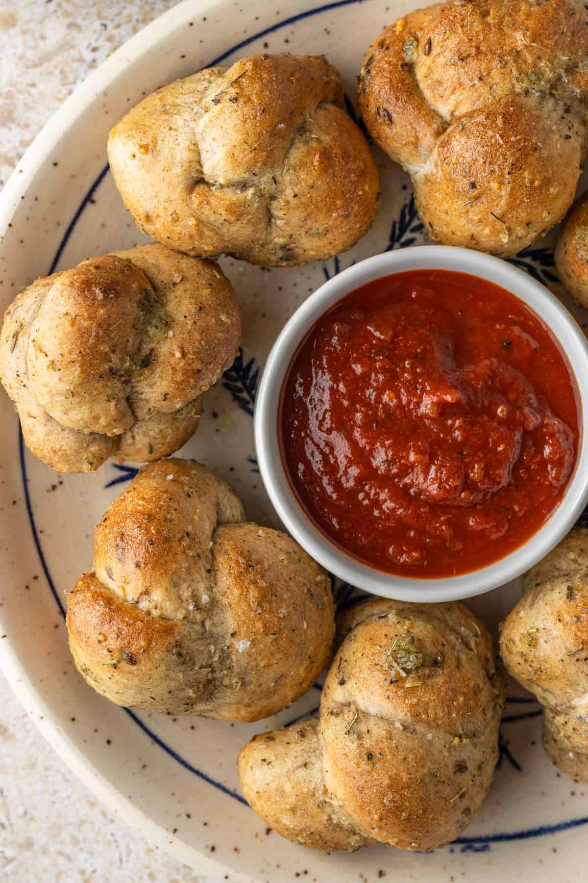 Air fryer garlic knots on a plate with marinara dipping sauce. 