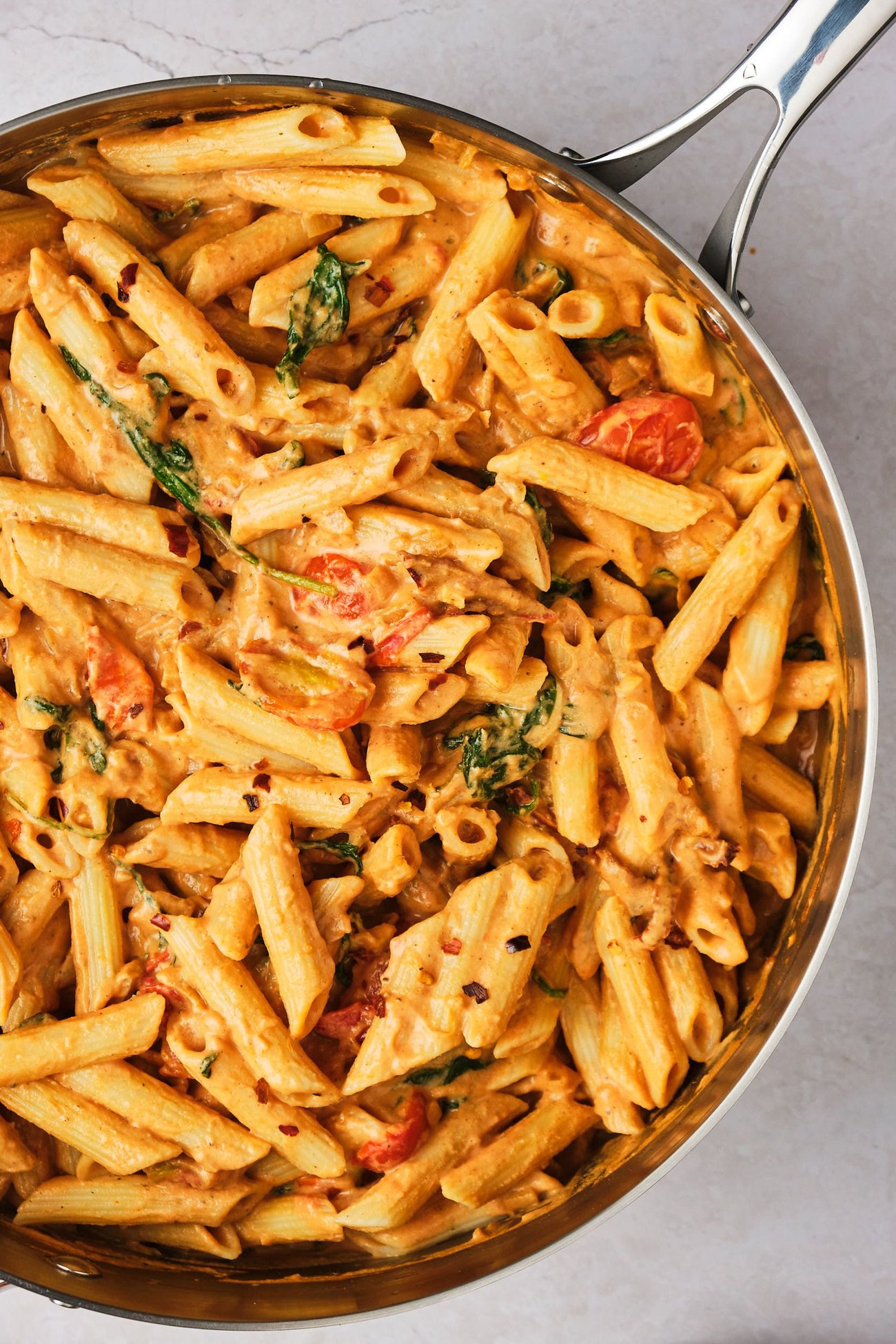 Creamy tomato pasta in a large skillet on a table. 