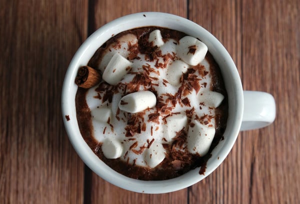 Foamy hot cacao with maca root topped with marshmallows, chocolate, and a cinnamon stick