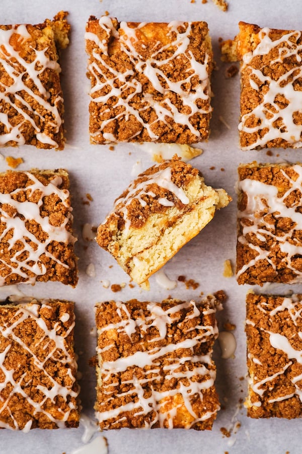 Pieces of vegan coffee cake on parchment paper, with the center piece turned to the side to show the layers of the cake. 