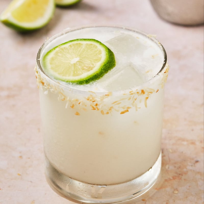 A coconut margarita in a glass rimmed with toasted coconut. 