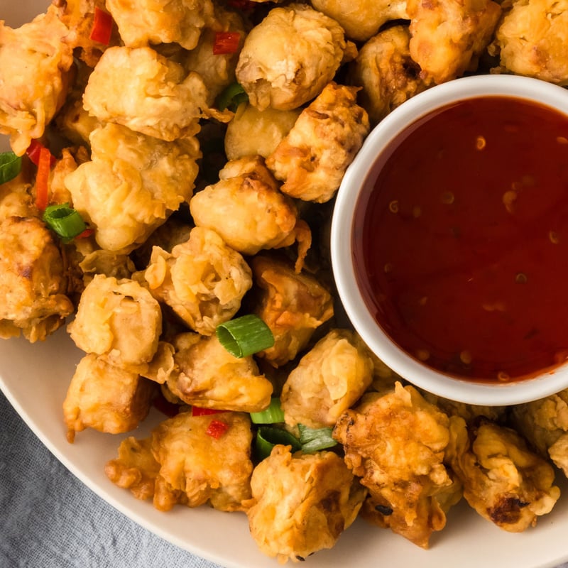 Crispy fried tofu in a bowl with sweet chili sauce.