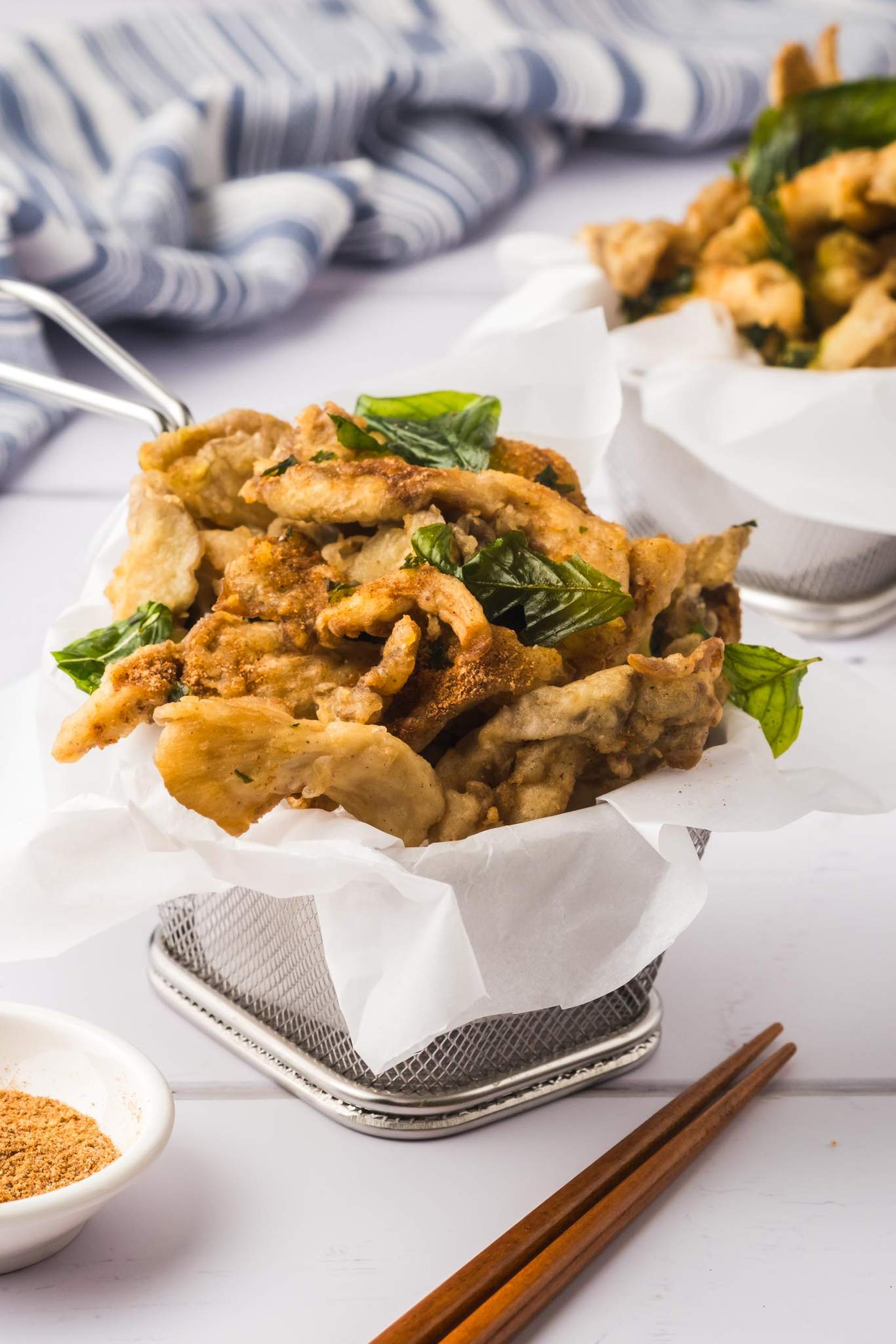 Two baskets of fried oyster mushrooms, with chopsticks and seasoning powder.